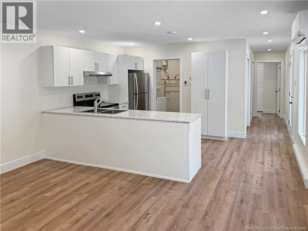 A kitchen with white cabinets and a wooden floor.