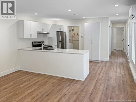 A kitchen with white cabinets and a wooden floor.