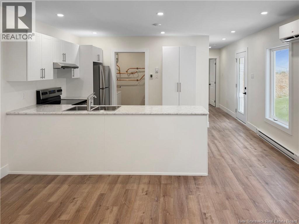 A modern kitchen with white cabinets and a wooden floor.