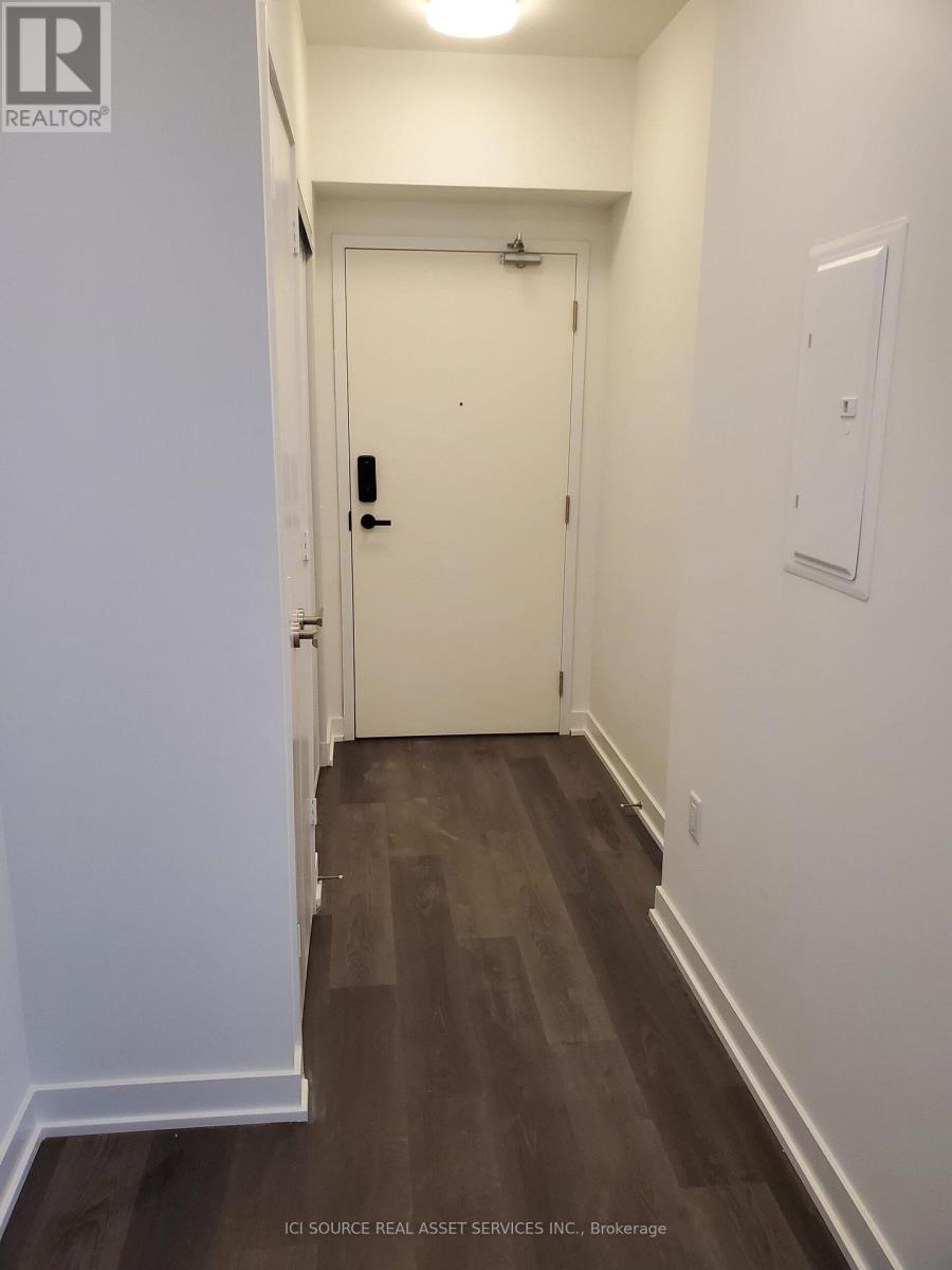 A hallway with a white door and a light switch on the wall.