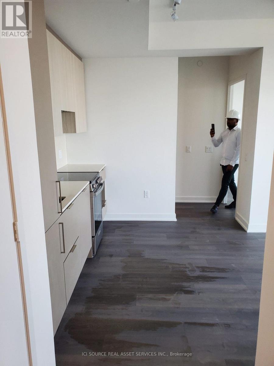 A man in a white shirt and black pants is standing in a room with white walls and a wooden floor.