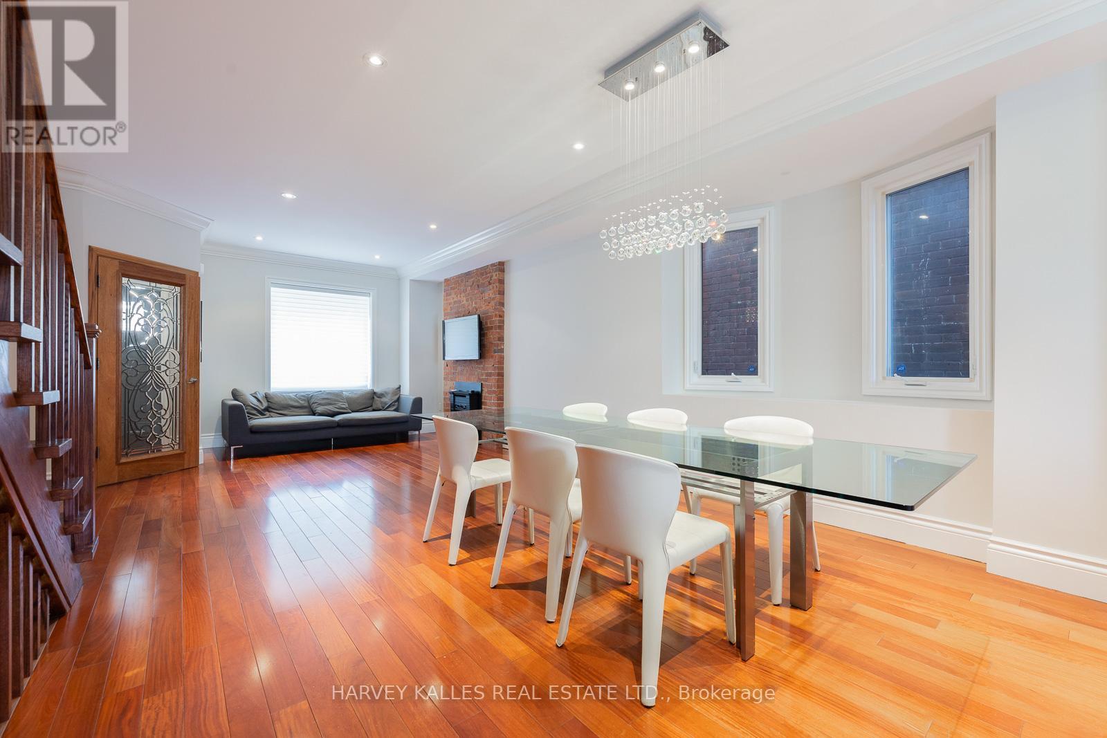 A dining room with a glass table and white chairs.
