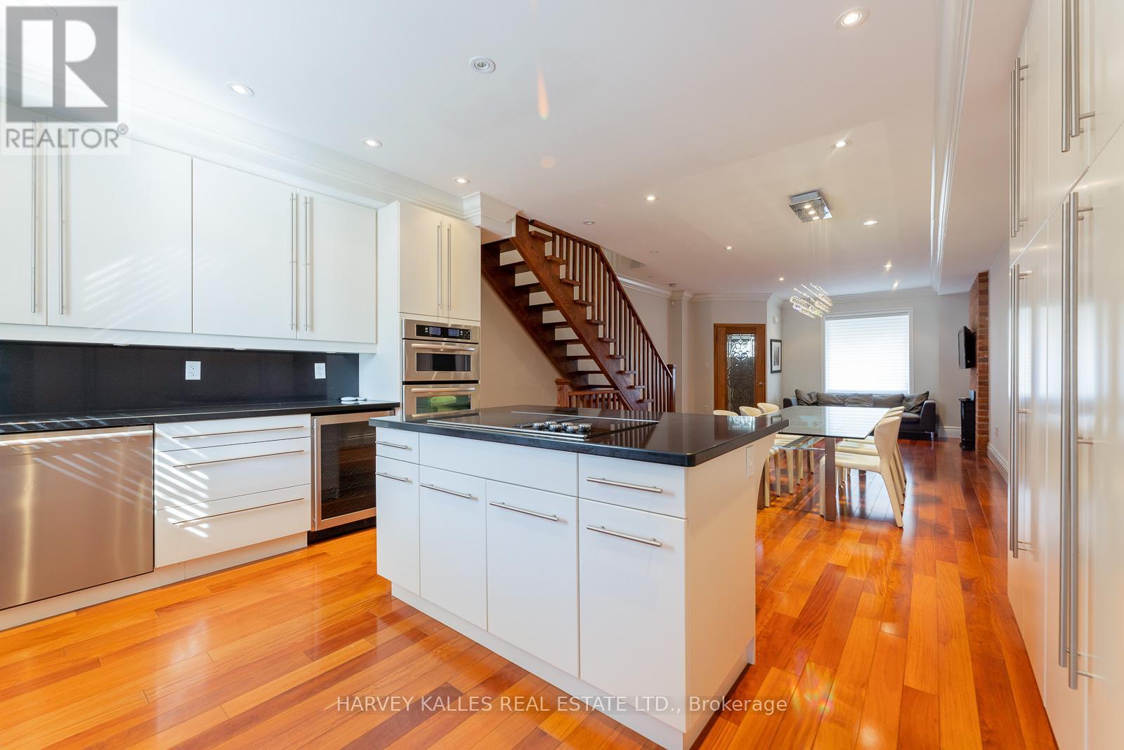 A modern kitchen with white cabinets and a wooden floor.