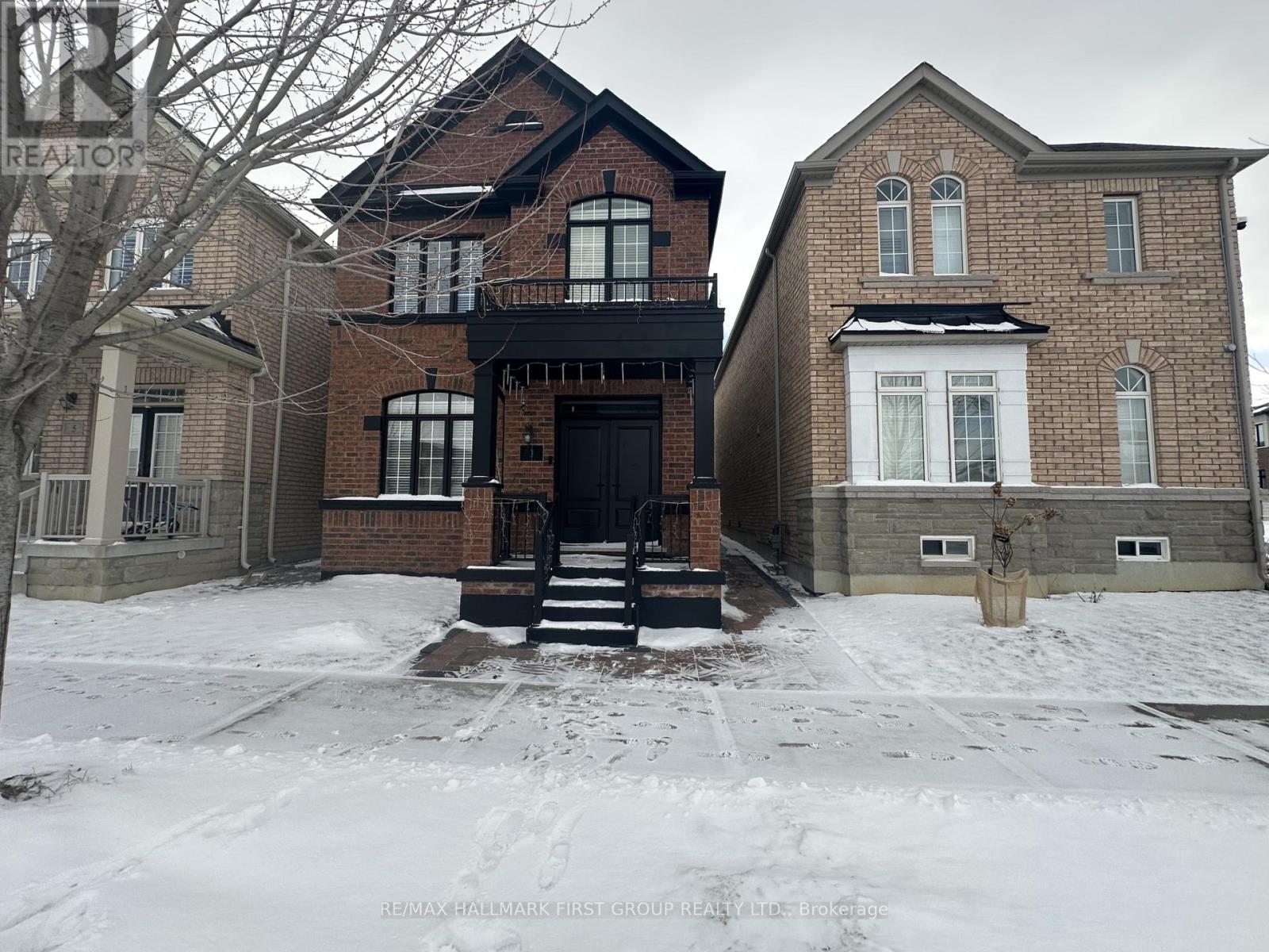 A large brick house with a black front door and steps leading to it.