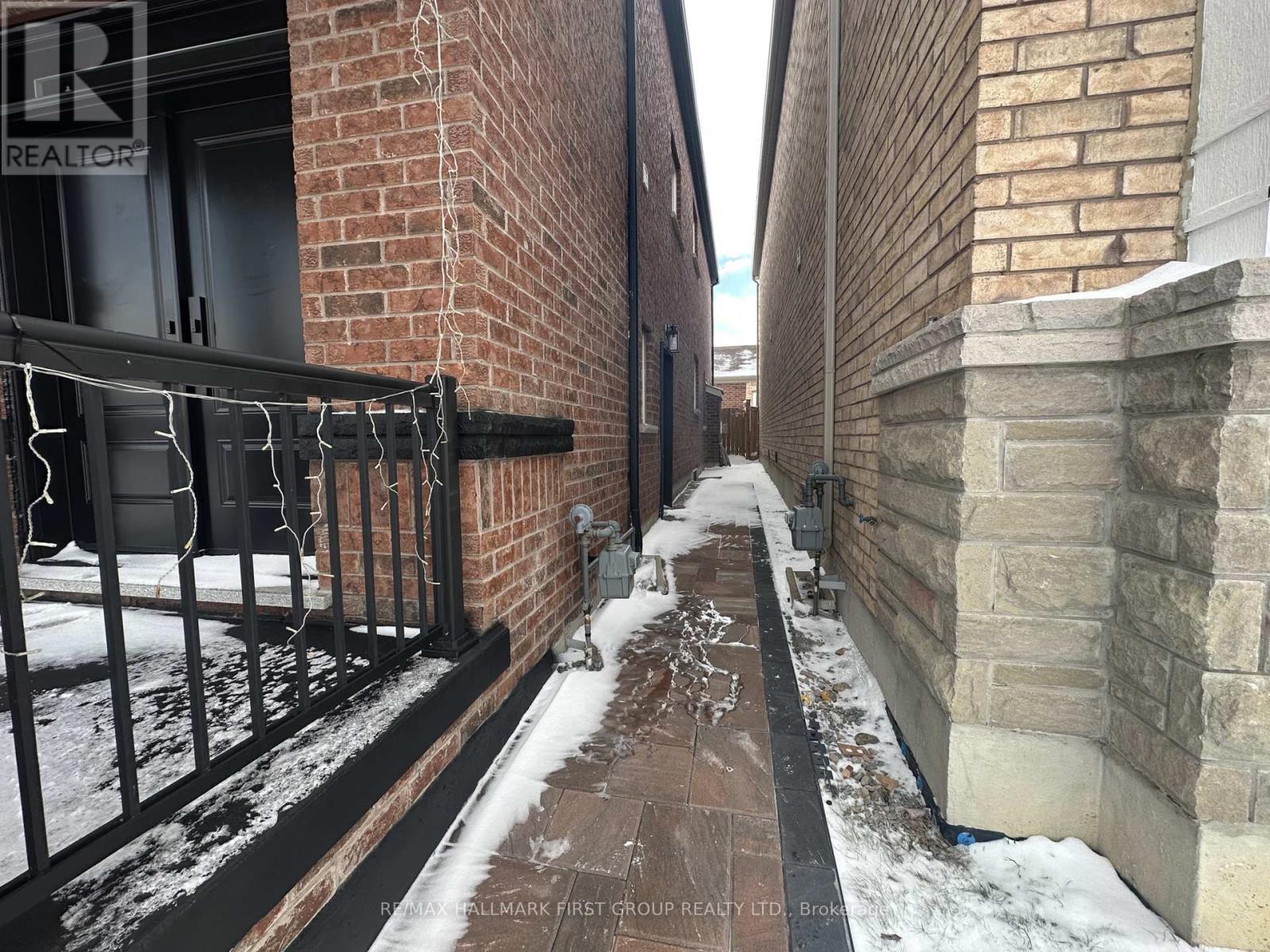 A snowy alley between two buildings with a Realty sign on the wall.