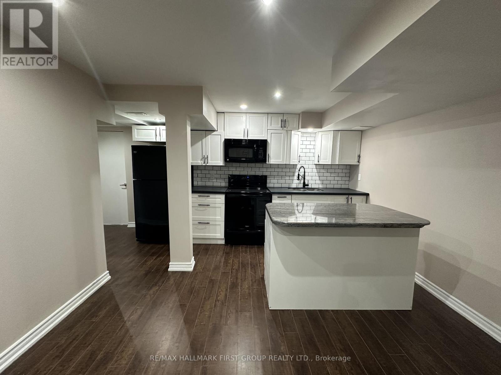 A kitchen with a black dishwasher and black oven with white cabinets and a white island.