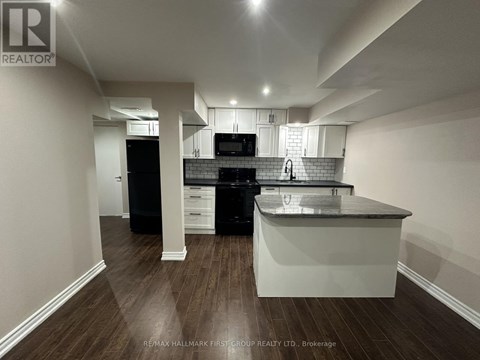 A kitchen with a black dishwasher and black oven with white cabinets and a white island.