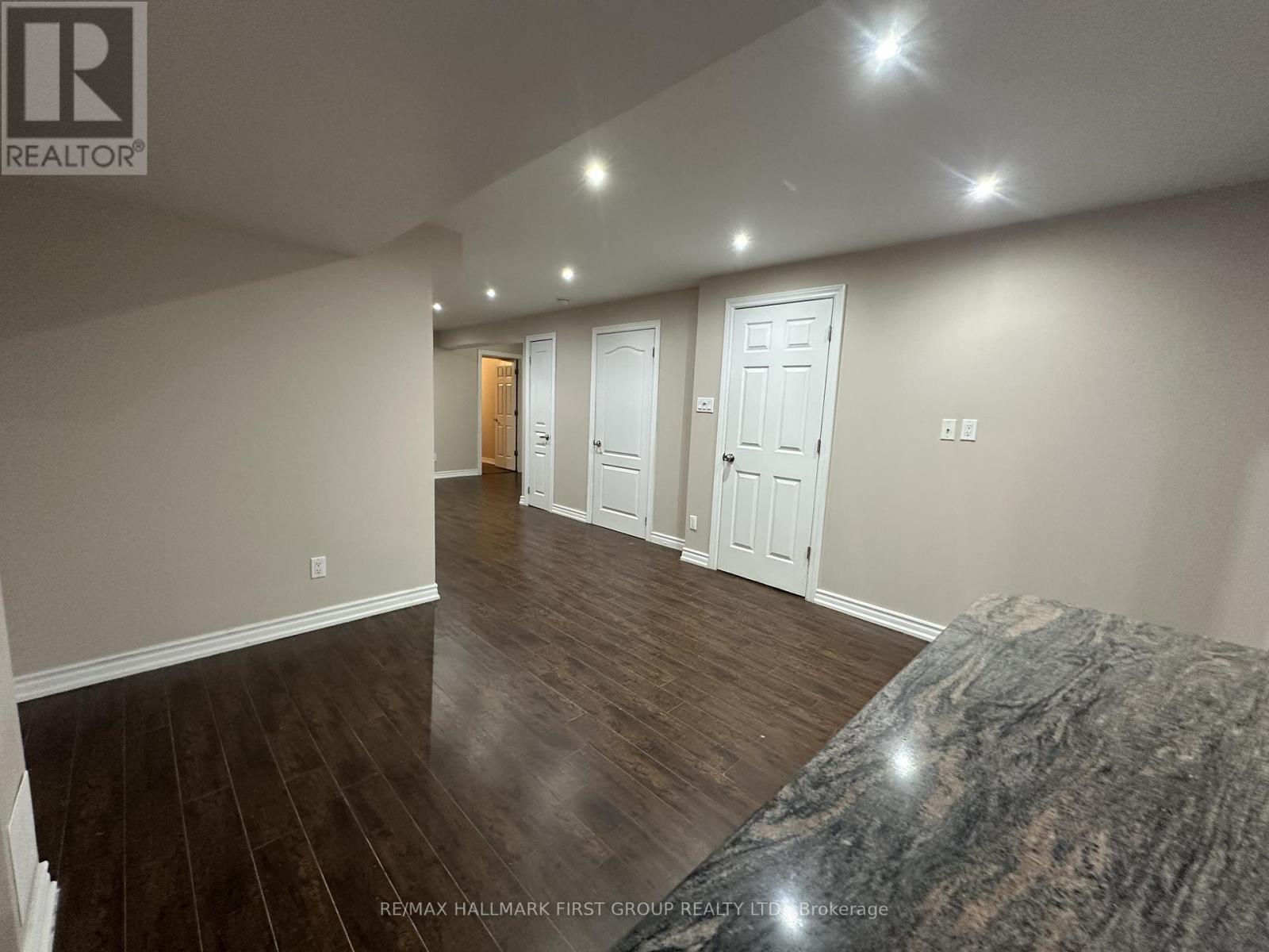 A spacious room with wooden floors and white walls, featuring a large bed with a marble headboard.