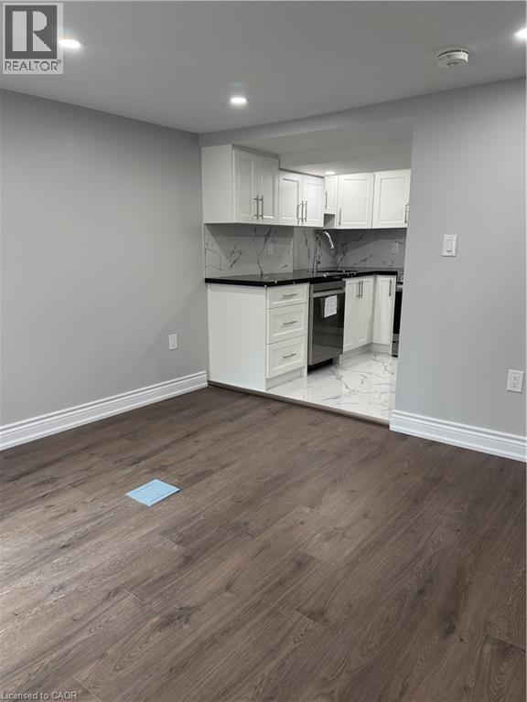 A kitchen with white cabinets and a wooden floor.