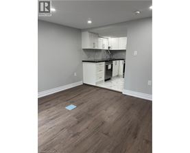 A kitchen with white cabinets and a wooden floor.