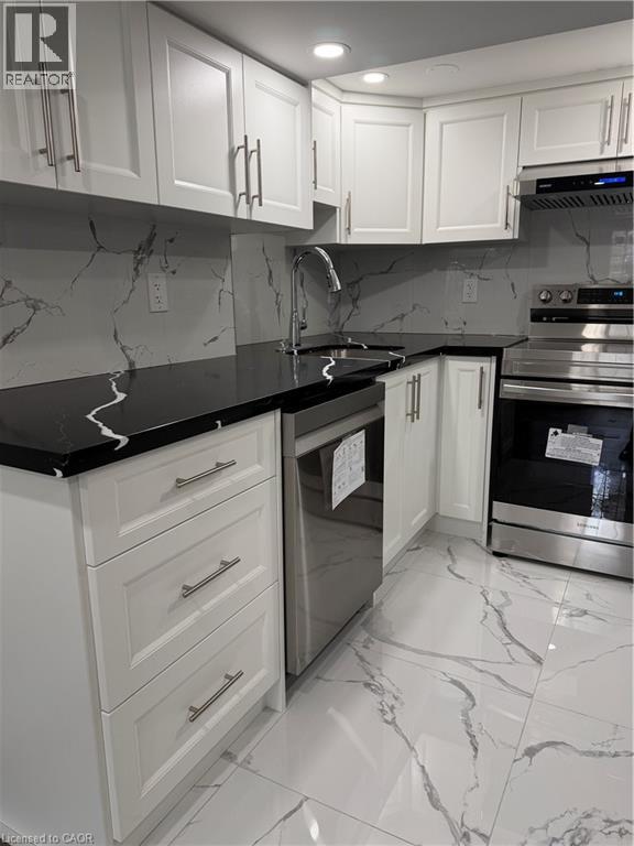 A kitchen with white cabinets and marble countertops.