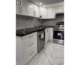 A kitchen with white cabinets and marble countertops.