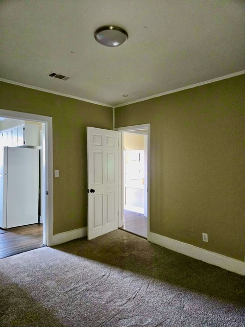 A room with a white door and a brown carpet.