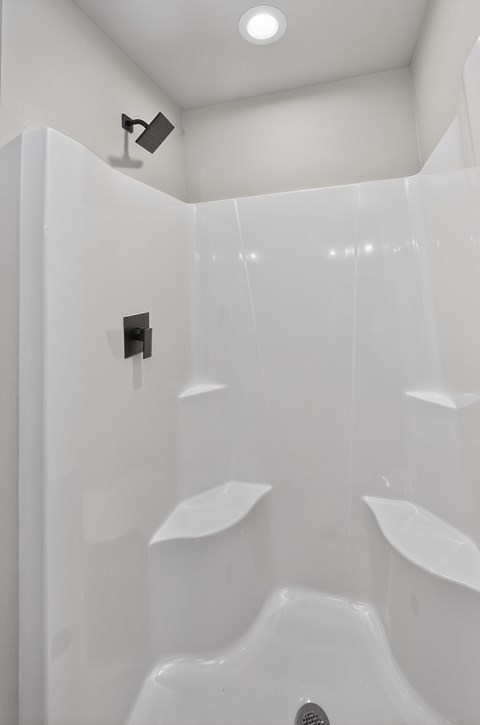 A white bathroom with a shower and a ceiling light.