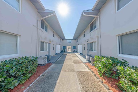 A sunny day in a long, narrow courtyard between two rows of identical buildings.