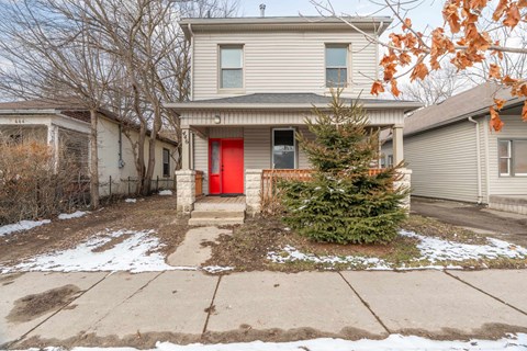 A house with a red door is surrounded by other houses.