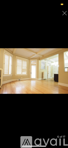 A spacious room with wooden floors and large windows.