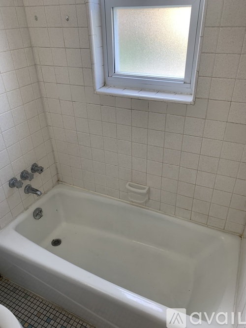 A white bathtub with a window above it.