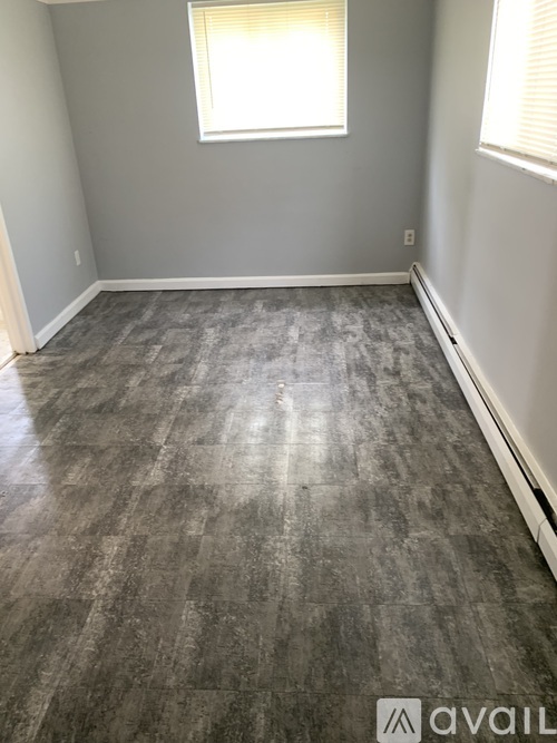 A room with a grey floor and a window with blinds.