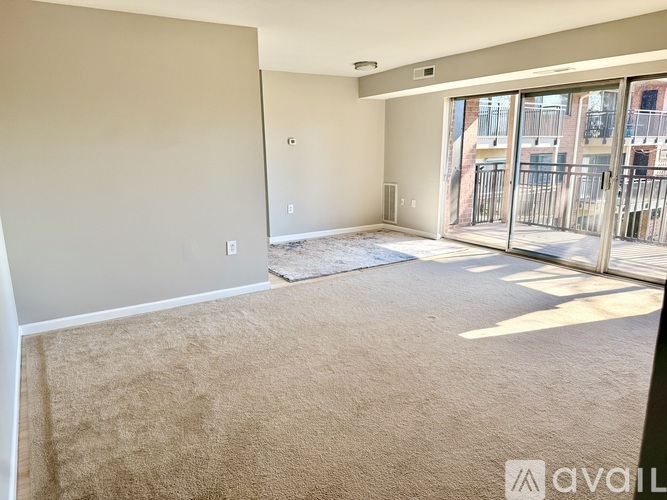 A spacious living room with a carpeted floor and sliding glass doors leading to a balcony.