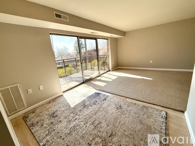 A spacious room with a carpeted floor and a sliding glass door leading to a balcony.