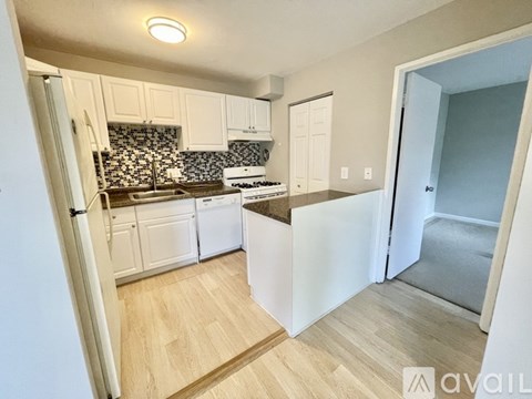A kitchen with white cabinets and a wooden floor.