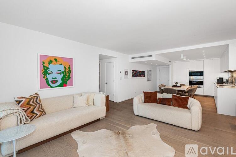 A living room with a white couch and a painting on the wall.