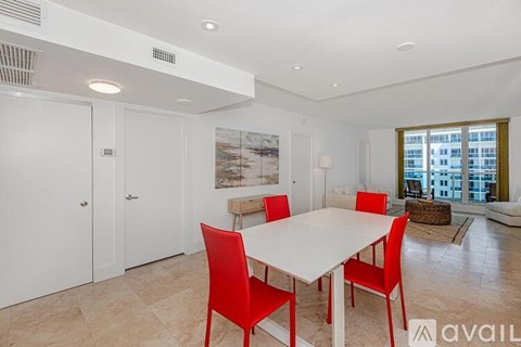 A dining room with a white table and red chairs.