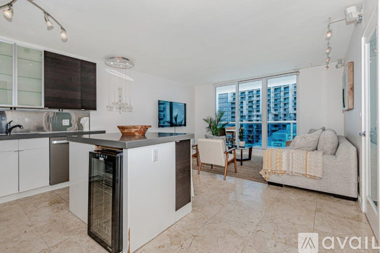 A kitchen with a refrigerator, a dining table with chairs, and a couch with a throw pillow.