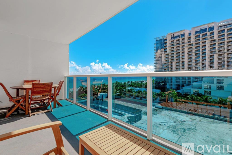 A balcony with a table and chairs overlooking a pool and a building.