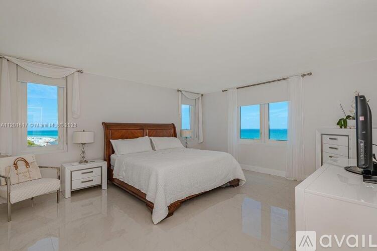 A bedroom with a large bed, a chair, and a nightstand with a lamp.