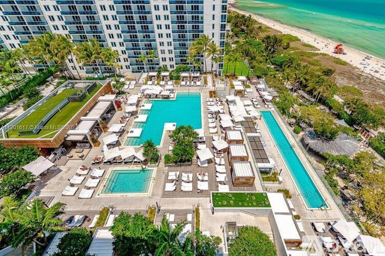 An aerial view of a resort with a large swimming pool and beachfront location.