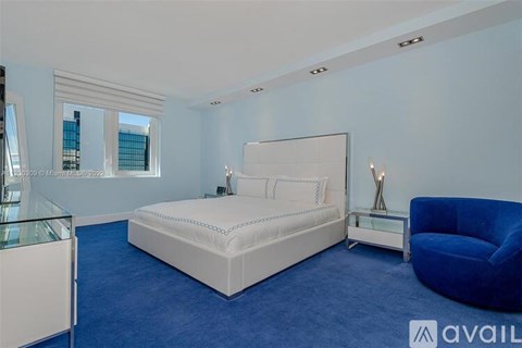 A bedroom with a white bed and blue carpet.