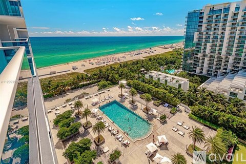 A view from a high-rise building overlooking a pool and beach area.