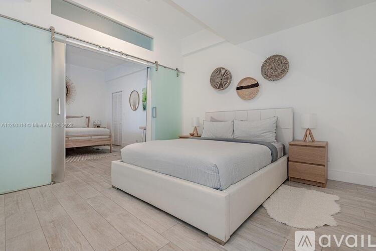 A bedroom with a large bed, a nightstand, and a mirror on the wall.