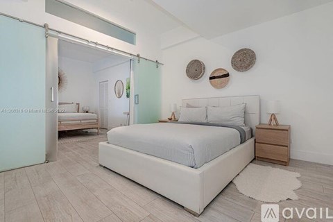 A bedroom with a large bed, a nightstand, and a mirror on the wall.