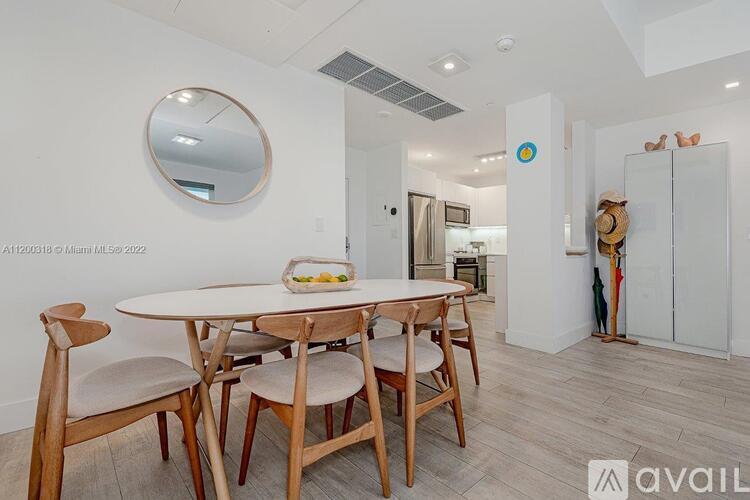 A dining room with a round mirror and a table with chairs.