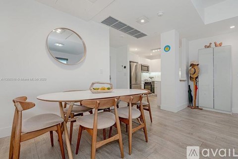 A dining room with a round mirror and a table with chairs.