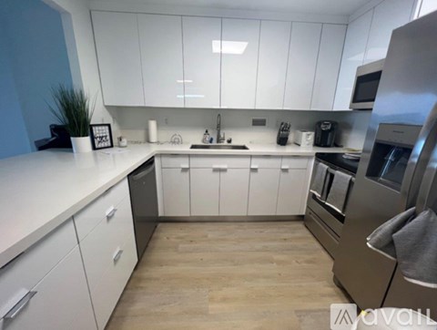 A modern kitchen with white cabinets and stainless steel appliances.