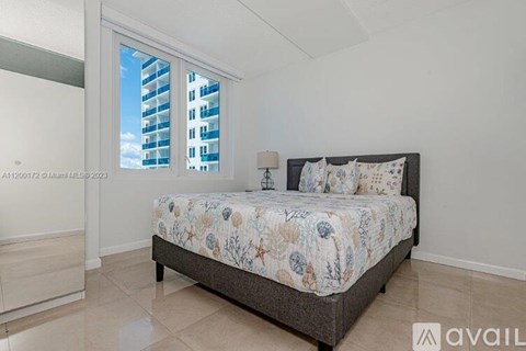 A bedroom with a large bed and a window overlooking a building.