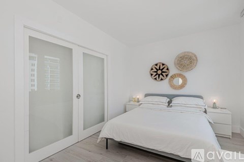 A bedroom with a white bed and a wreath on the wall.