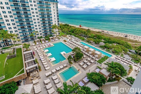 A large pool area with sun loungers and a view of the sea.