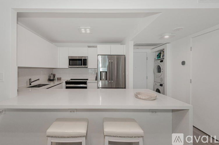 A modern kitchen with white cabinets and appliances.