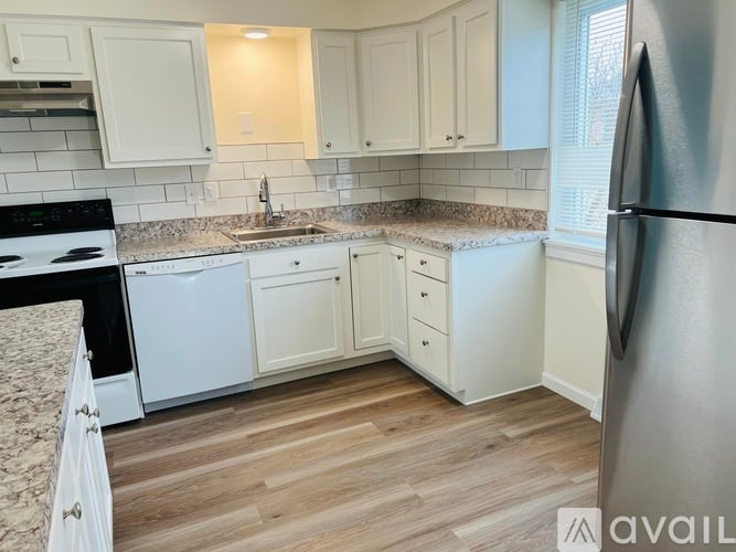 A kitchen with white cabinets and a granite countertop.