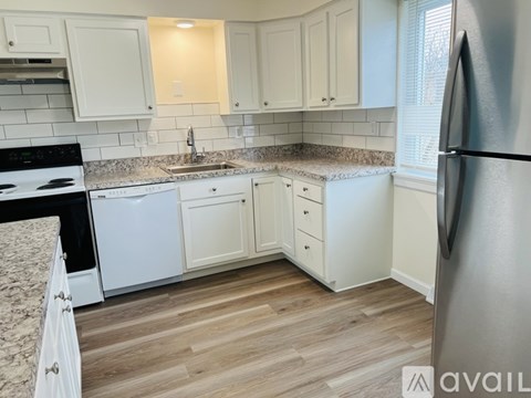 A kitchen with white cabinets and a granite countertop.