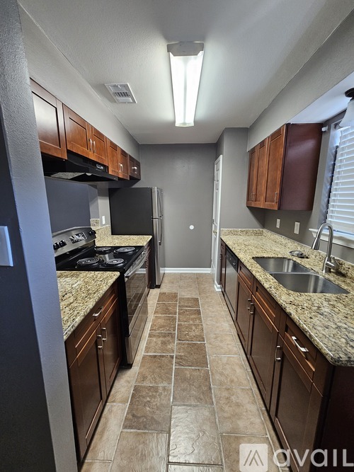 A kitchen with brown cabinets and a black stove top oven.