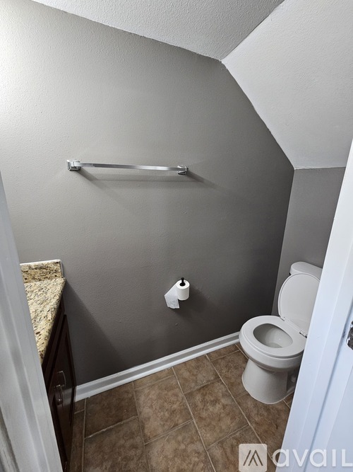 A toilet is in a small bathroom with a towel rack on the wall.