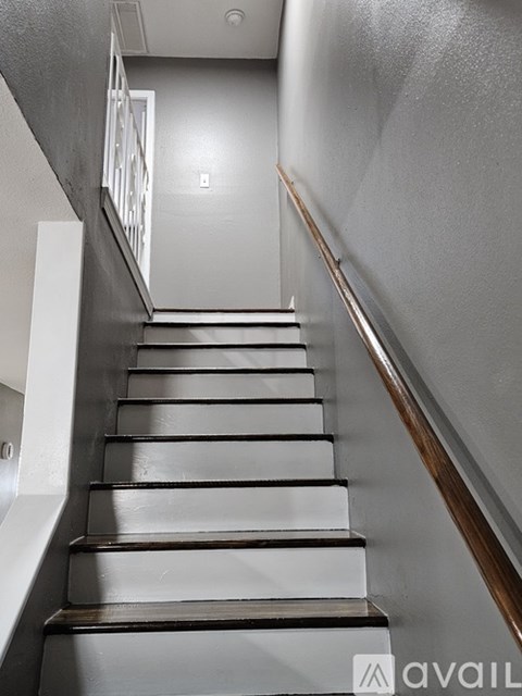 A staircase with a wooden handrail and white steps.