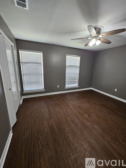 A room with a ceiling fan and wooden flooring.