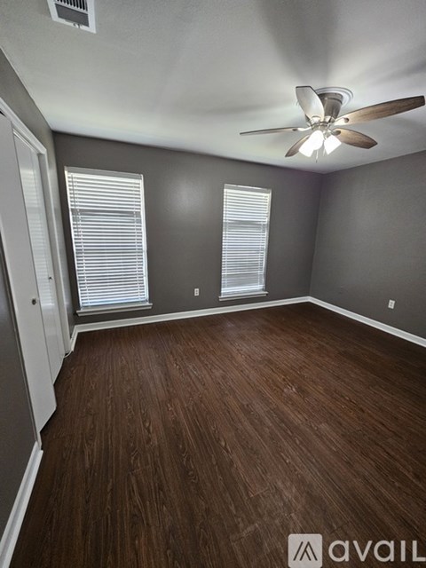 A room with a ceiling fan and wooden flooring.